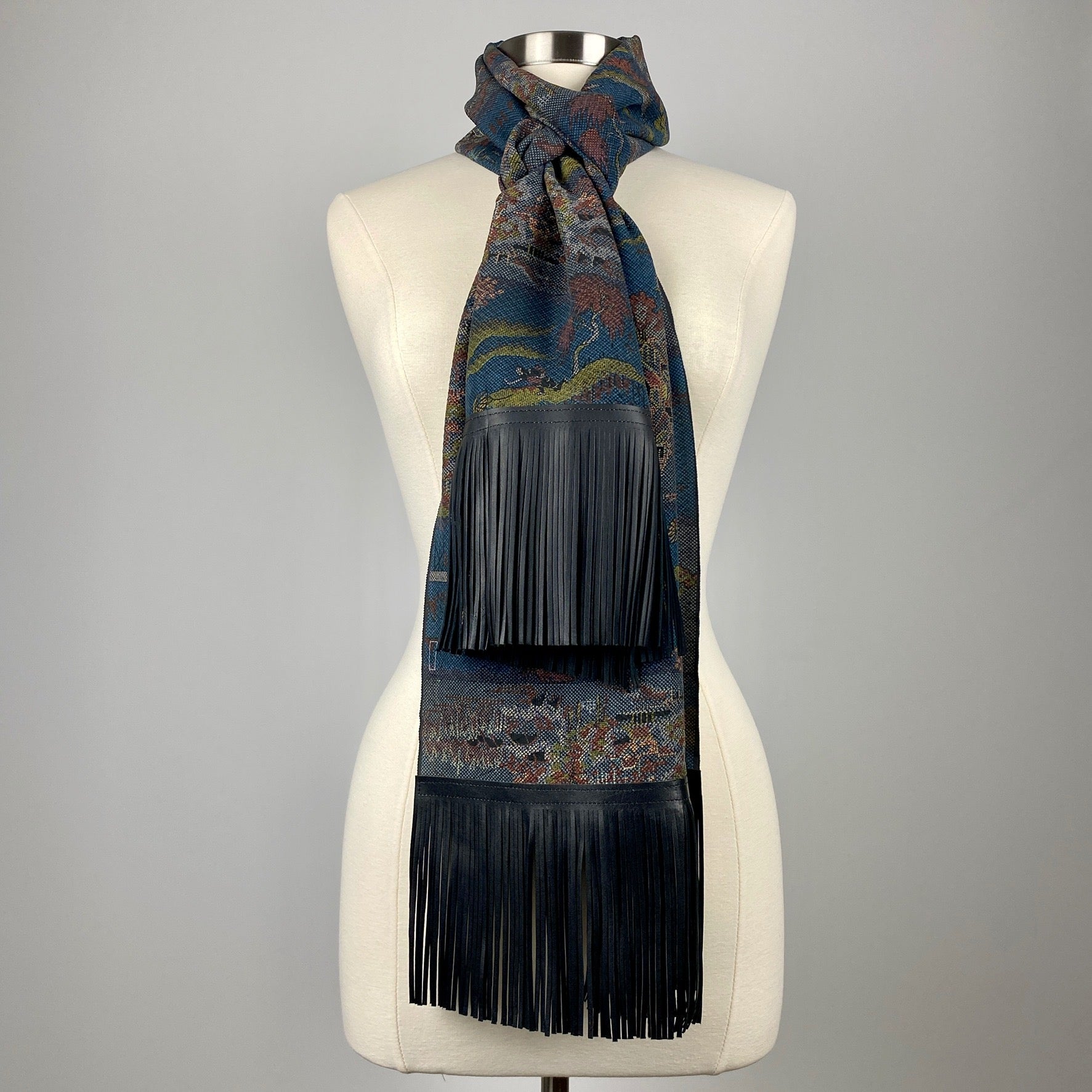 A dark blue kimono silk scarf with black leather fringe. Silk has scenery of people on a journey