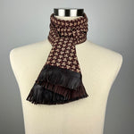 A brown and beige silk scarf with a geometric paulownia crest. The scarf has brown leather fringe and is tied as a double ascot.