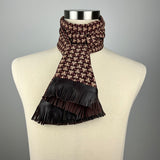 A brown and beige silk scarf with a geometric paulownia crest. The scarf has brown leather fringe and is tied as a double ascot.